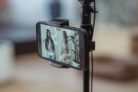 Celular gravando vídeo de duas mulheres conversando, em um tripé.