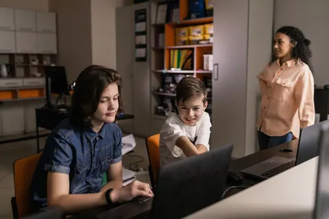 Jovens e crianças aprendendo tecnologia em um ambiente de sala de aula.