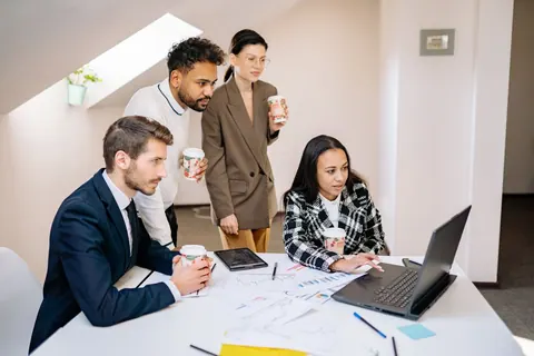 Grupo de empresários e mulheres olhando para um laptop em uma reunião de trabalho.