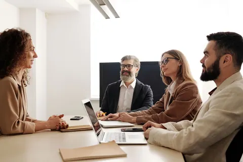 Entrevista de emprego com três gestores e uma candidata em uma sala de reunião.