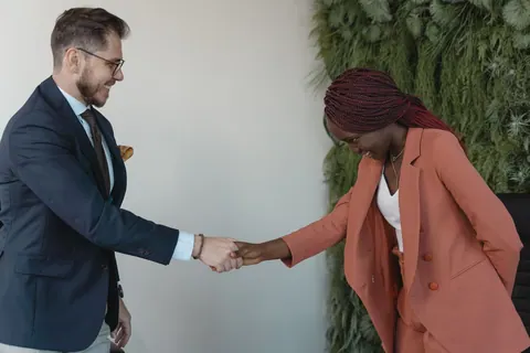 Homem e mulher de negócios apertando as mãos em um escritório moderno.