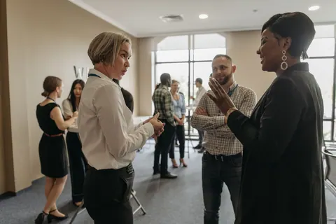 Profissionais de RH conversando animadamente em um evento corporativo.