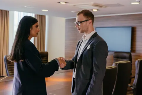 Dois profissionais se cumprimentando com um aperto de mãos em uma sala de reunião.