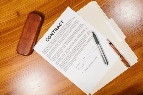 Contrato de trabalho sobre uma mesa de madeira, com caneta e pasta de documentos.