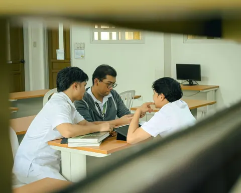 Três pessoas, possivelmente professor e alunos, colaborando em uma mesa de estudo.