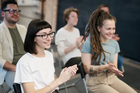 Público sorridente aplaudindo durante evento profissional