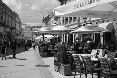 Rua de pedestres com restaurantes ao ar livre e pessoas caminhando.