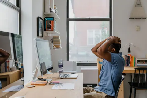 Homem com as mãos na cabeça em um escritório, parecendo estressado ou sobrecarregado.
