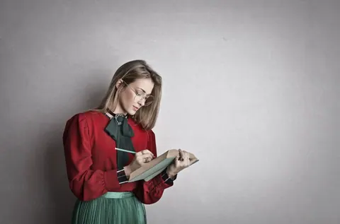Mulher estudando, escrevendo em um livro, simbolizando aprendizado e retenção.