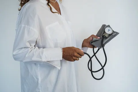 Mulher segurando um monitor de pressão arterial, simbolizando o acompanhamento da saúde.