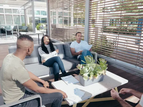 Pessoas de diversas etnias conversando em um ambiente de trabalho descontraído e moderno.