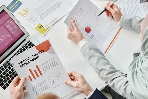 Pessoas analisando relatórios financeiros com gráficos e dados em uma mesa