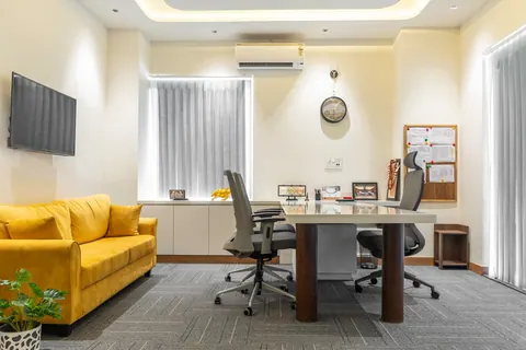 Escritório moderno e elegante com sofá amarelo, mesa de trabalho e cadeiras.