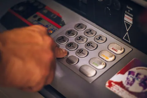 Pessoa digitando a senha em um caixa eletrônico.