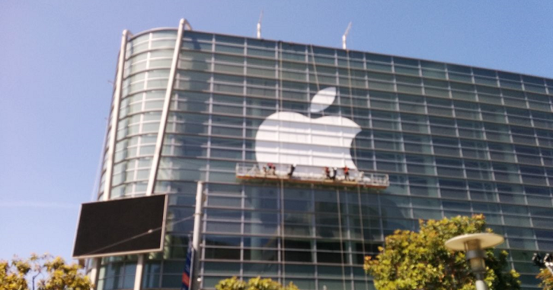 Funcionários instalam logo da apple na fachada do prédio